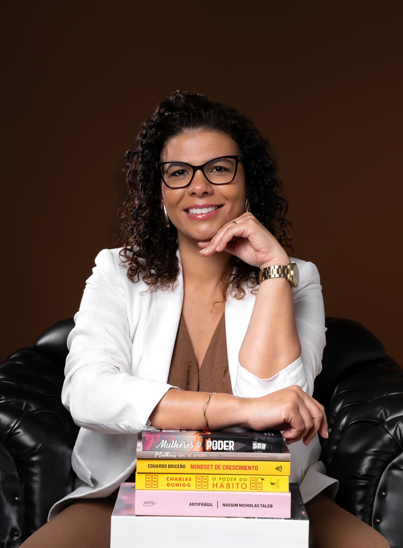 Flavia Monteiro apoiada em uma pilha de livros, sorrindo